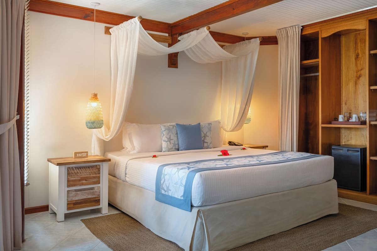 A bedroom with a canopy bed, bedside tables, a wardrobe, and a nightstand.