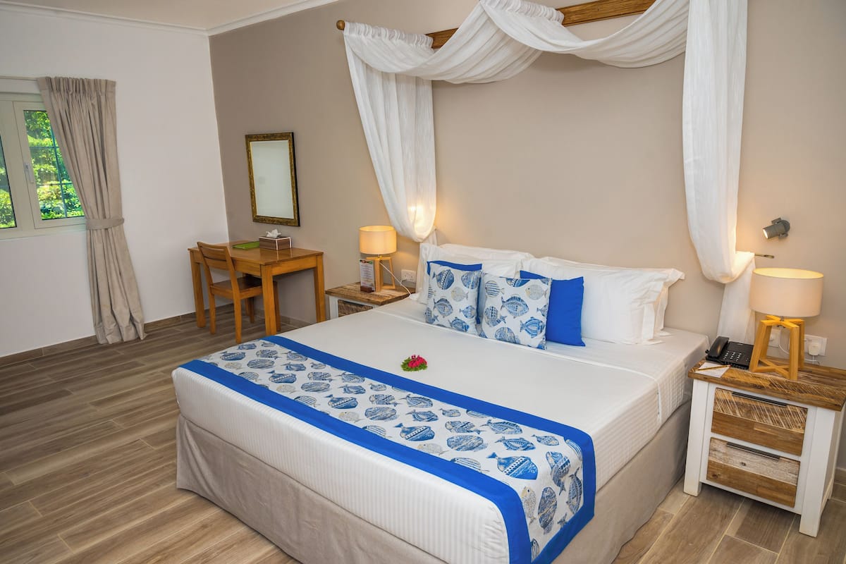 A bedroom with a bed, bedside tables, a desk, and a window with curtains.