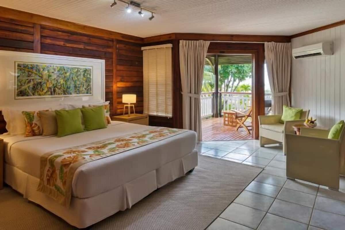 A bedroom with a bed, nightstands, a desk, a chair, and a view of the outdoors.