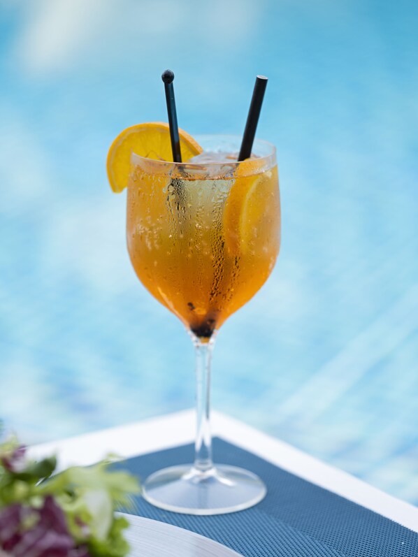 A cocktail glass with a lemon slice and two straws, placed on a blue tablecloth. - Acajou Beach Resort (Praslin Island)