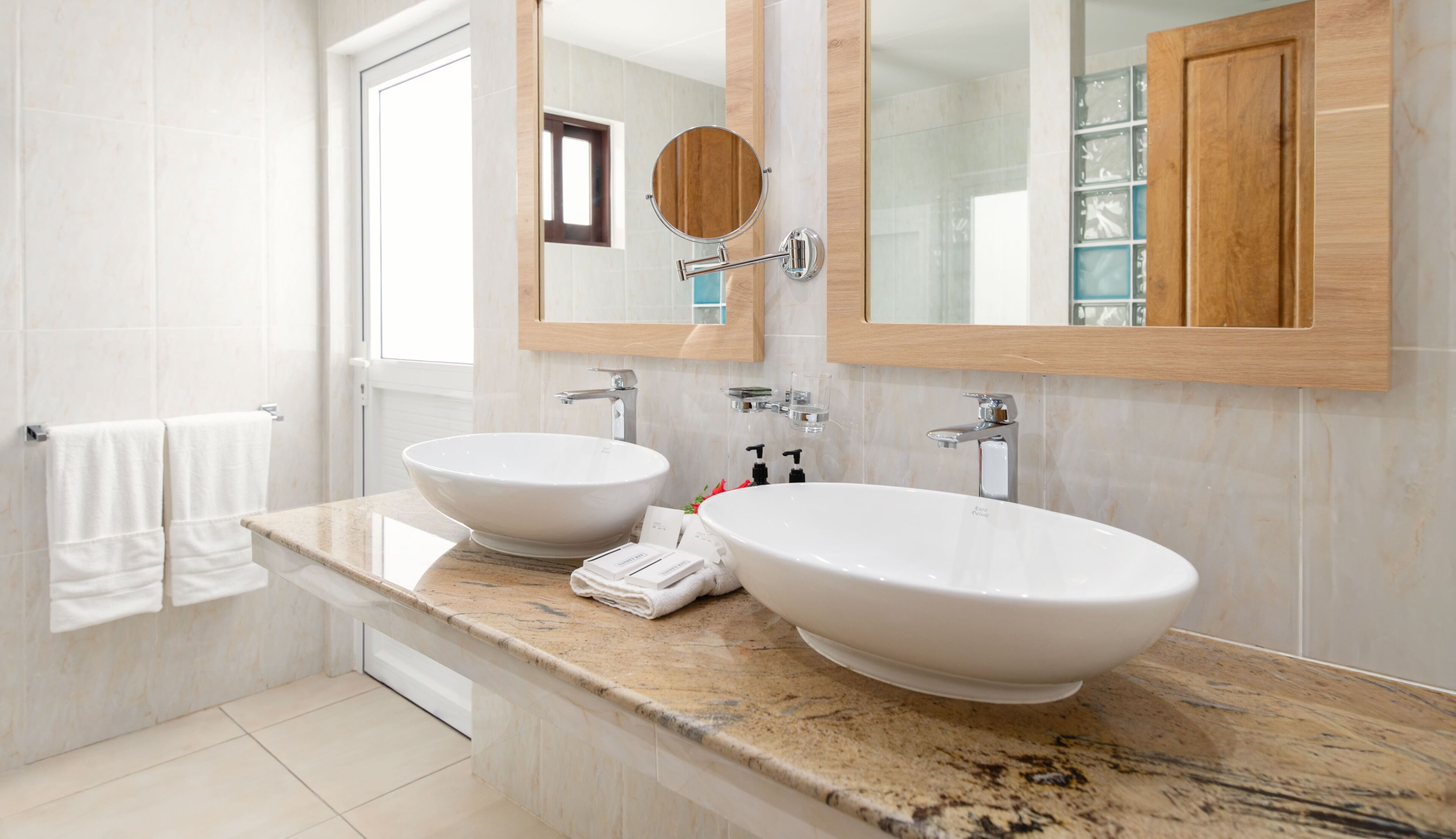 Un bagno con due lavandini, uno specchio e una finestra.