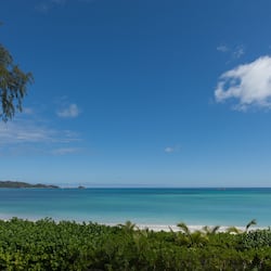Na praia, areia branca, espreguiçadeiras, guarda-sóis