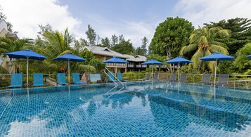 Una piscina al aire libre, sombrillas, sillones reclinables de piscina