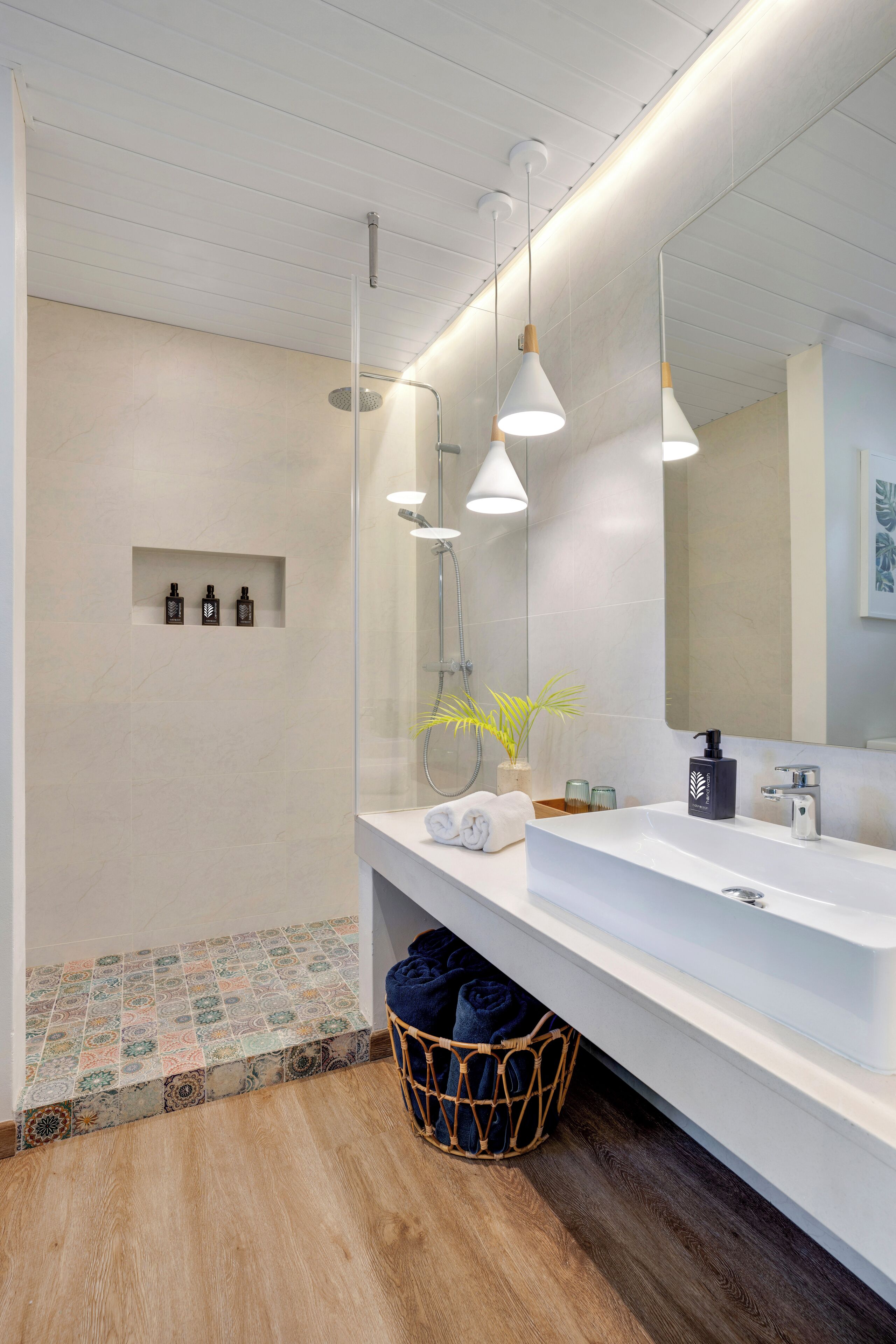 Casa de banho moderna com um espelho grande, toucador branco e zona de duche.