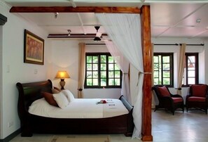 Quarto com cama, mesa de cabeceira, luminária e janela com cortinas.
