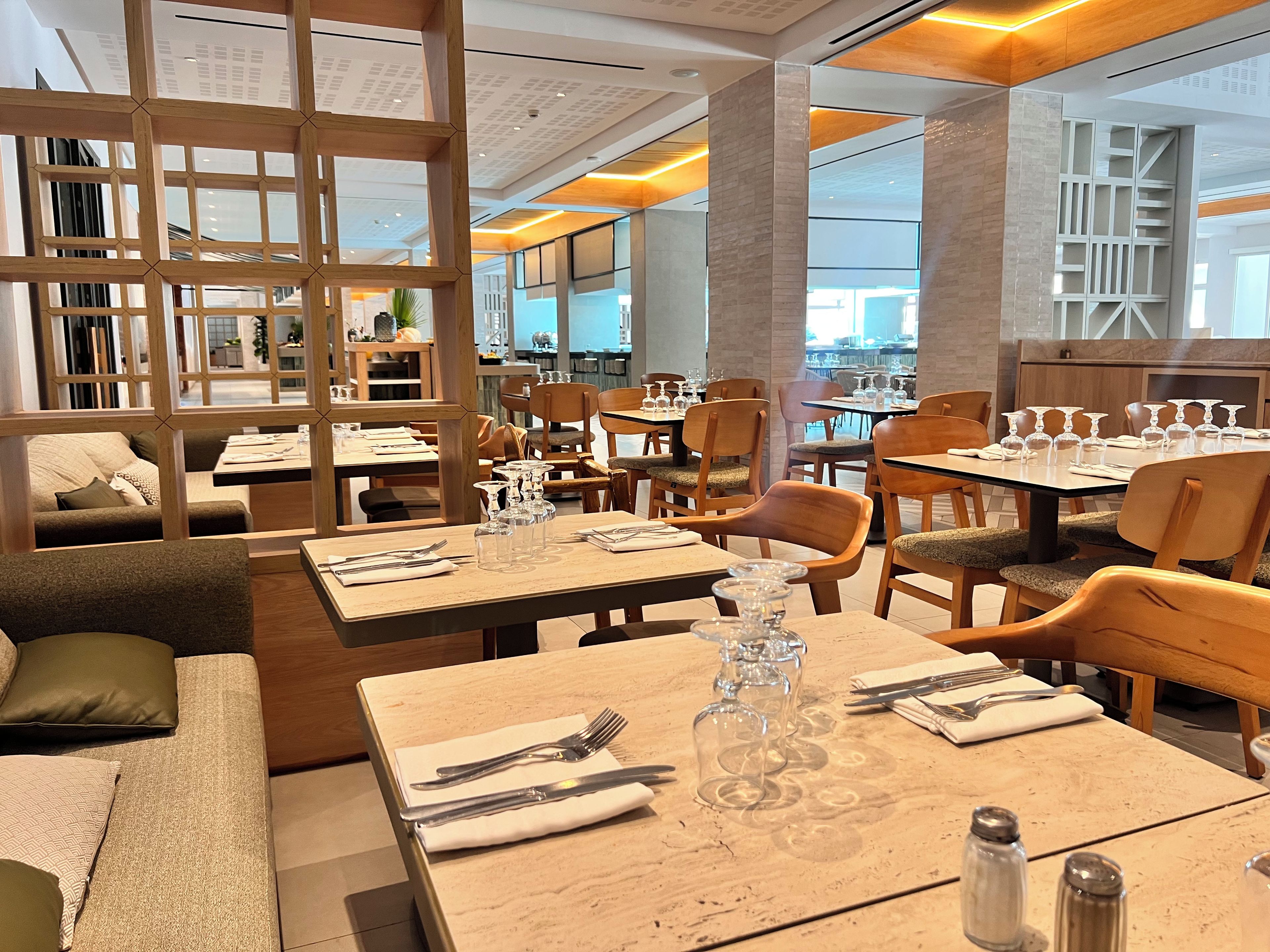 L’intérieur d’un restaurant, avec plusieurs tables, des chaises et une cloison en bois.