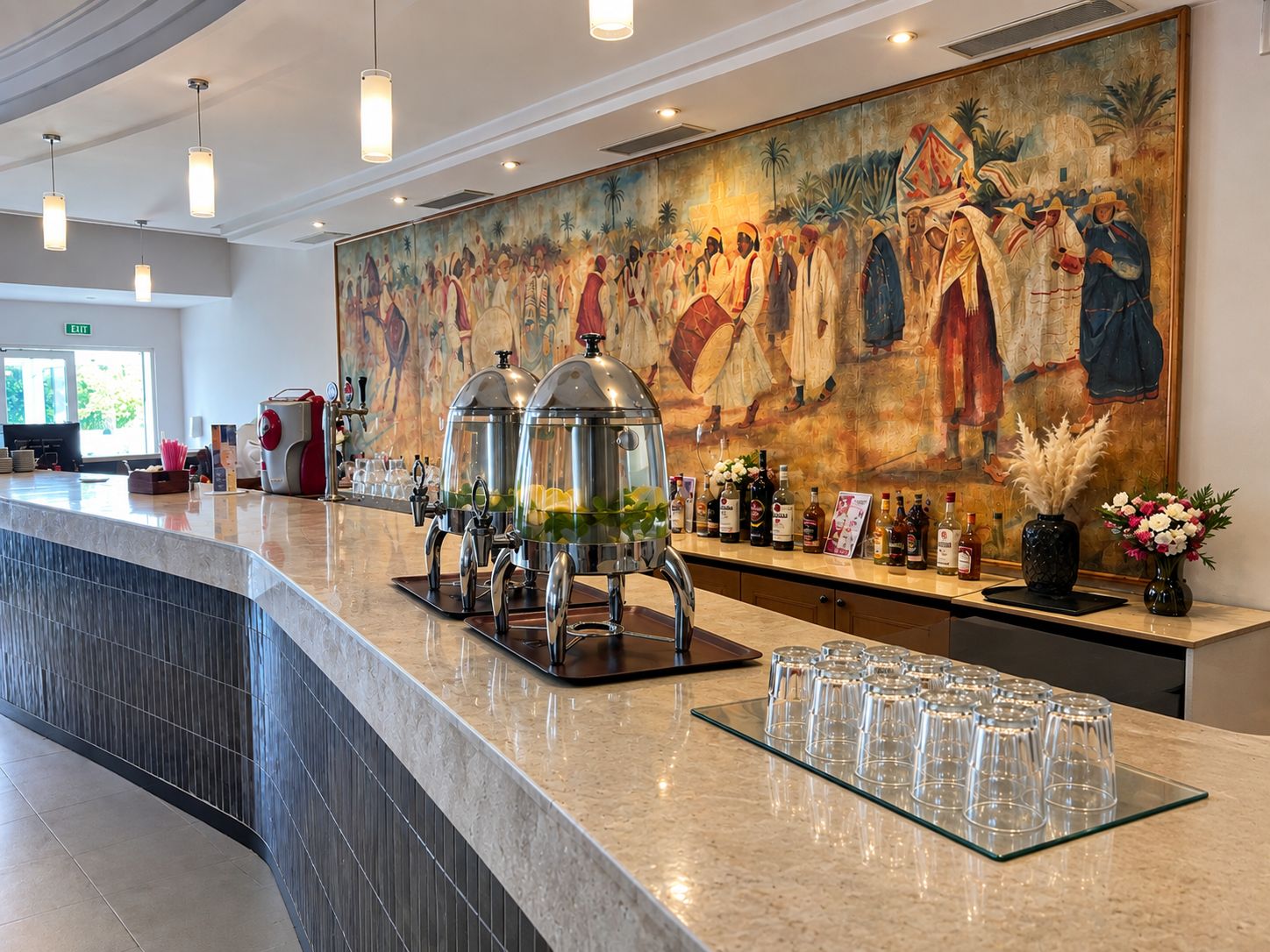 A hotel lobby with a marble reception desk, a large mural, and a bar area with bottles and glasses.