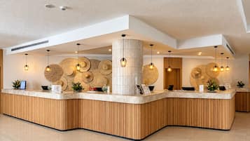 A reception desk with a wooden finish, a white pillar, and woven wall decorations.