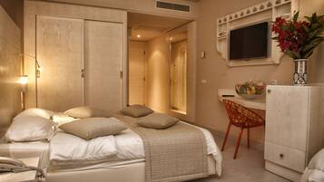 Una habitación de hotel con cama, mesita de noche, lámpara, escritorio, silla y televisor.