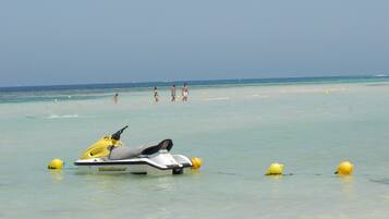 Un jet ski en una playa con aguas cristalinas y boyas amarillas.