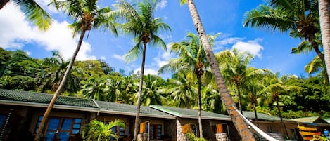 A resort with multiple bungalow-style buildings, palm trees, and a clear blue sky.