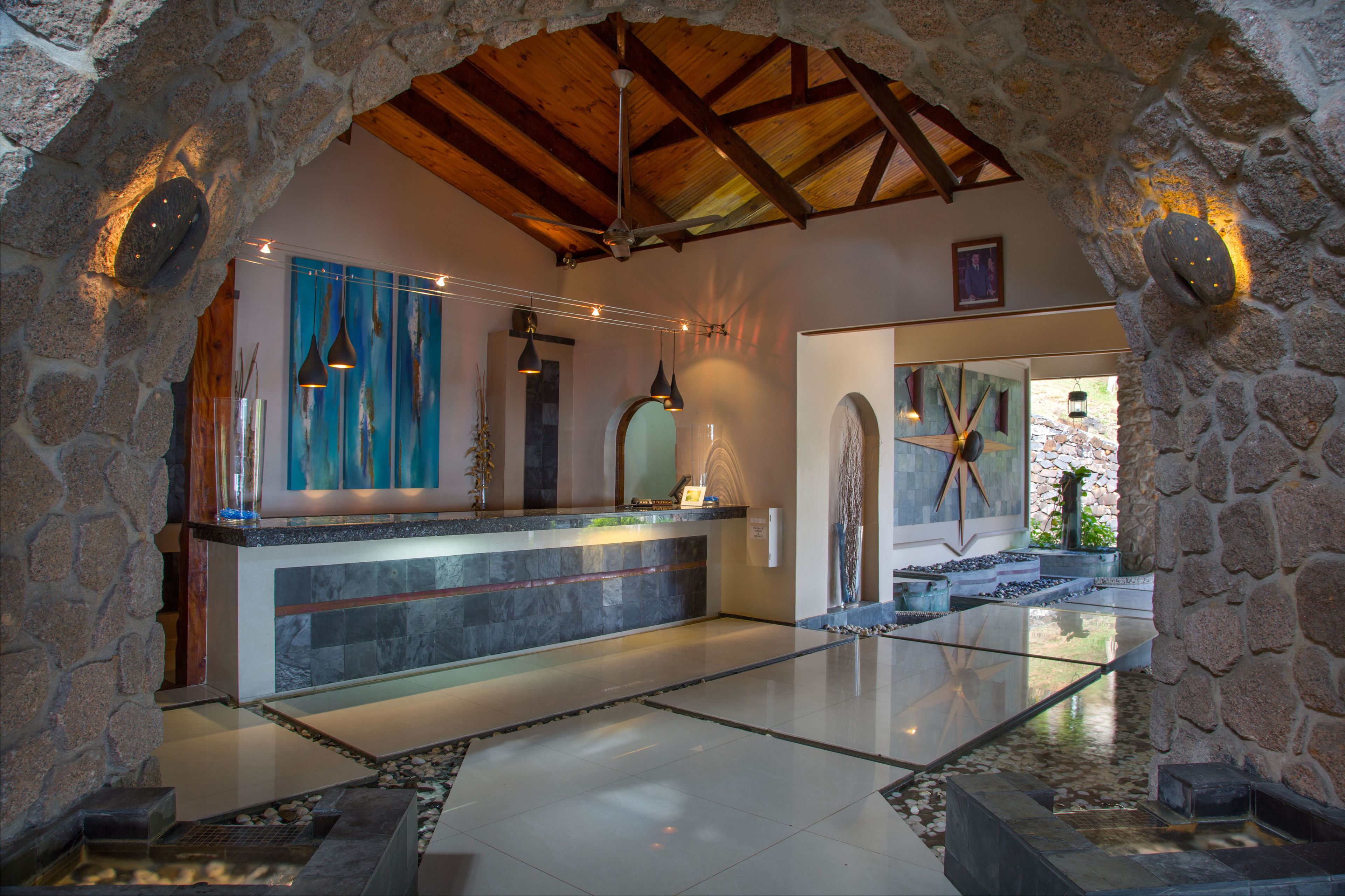 A stone-walled lobby with a reception desk, hanging pendant lights, and a starfish decoration.