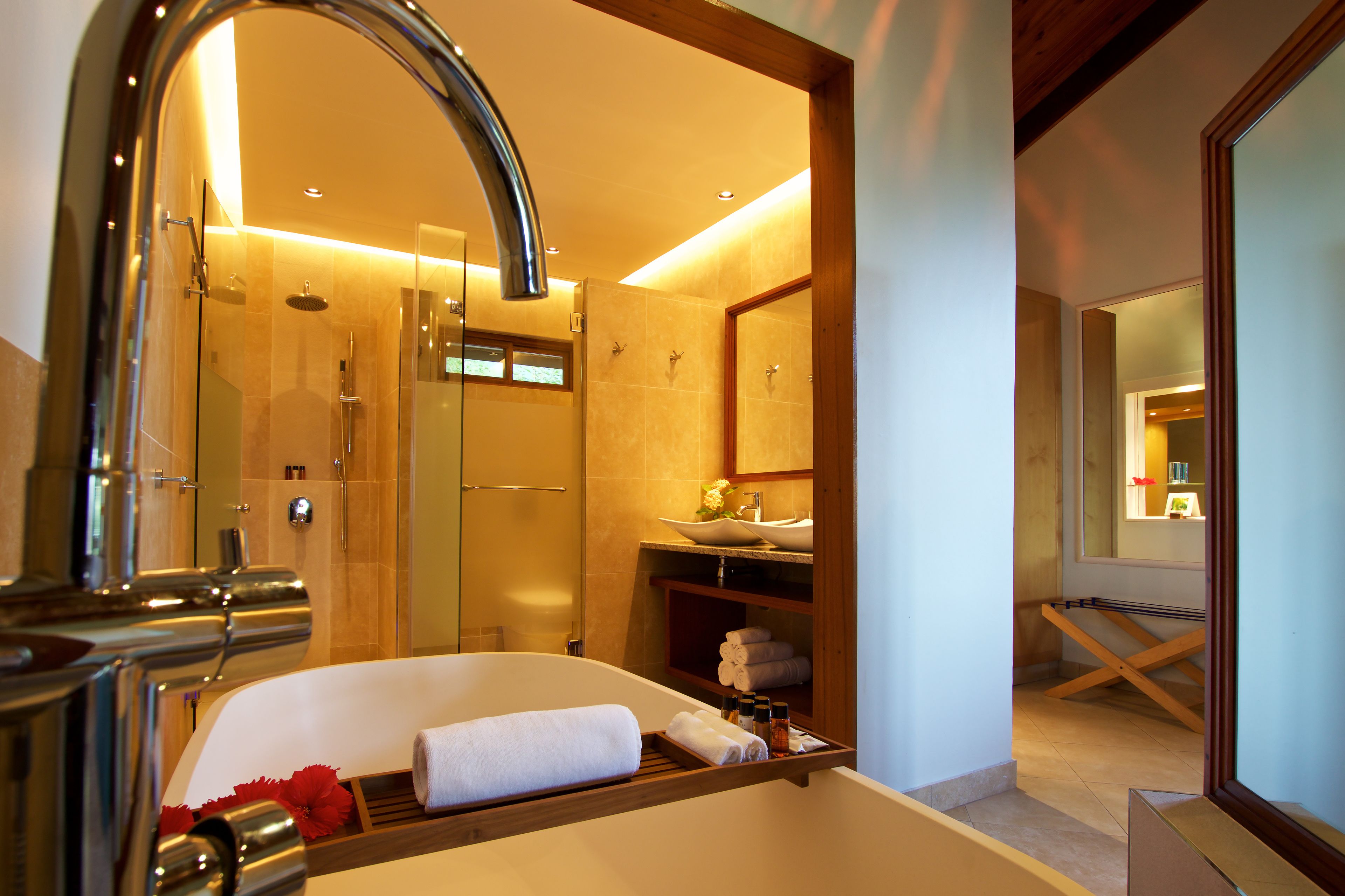 A modern bathroom with a large bathtub, a glass-enclosed shower, and a vanity with a sink and mirror.