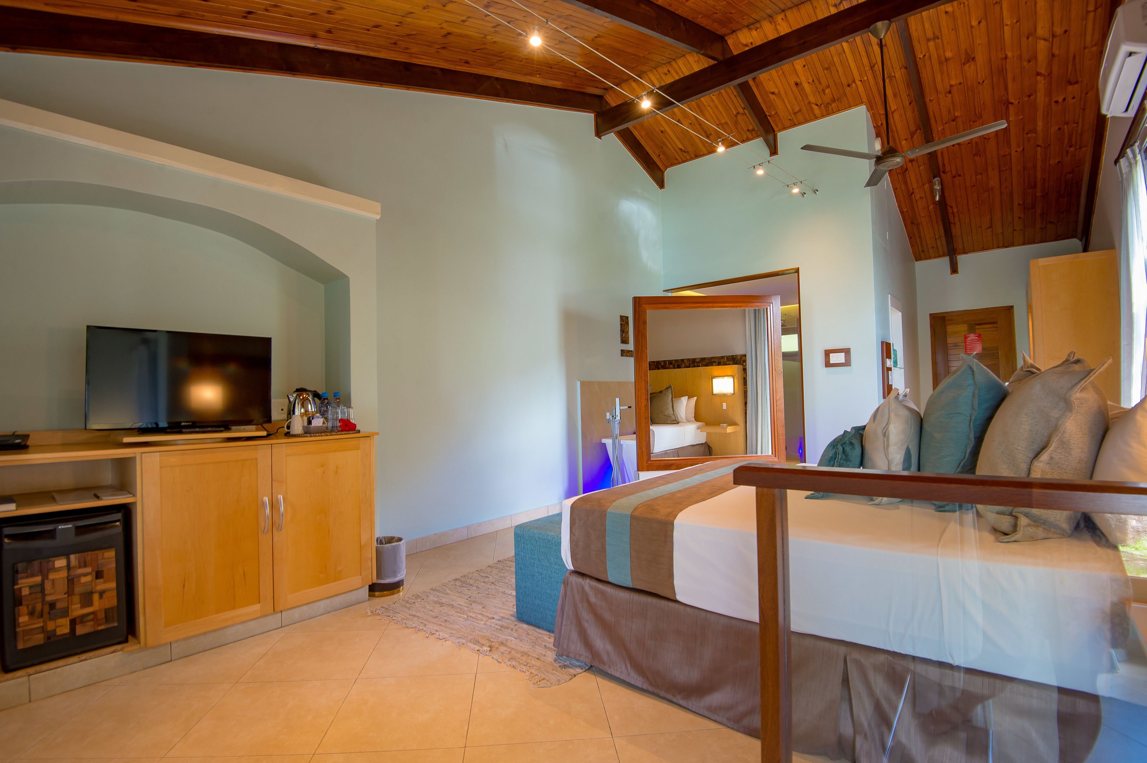 Une chambre d’hôtel avec un plafond en bois, une télévision, un canapé et un lit.