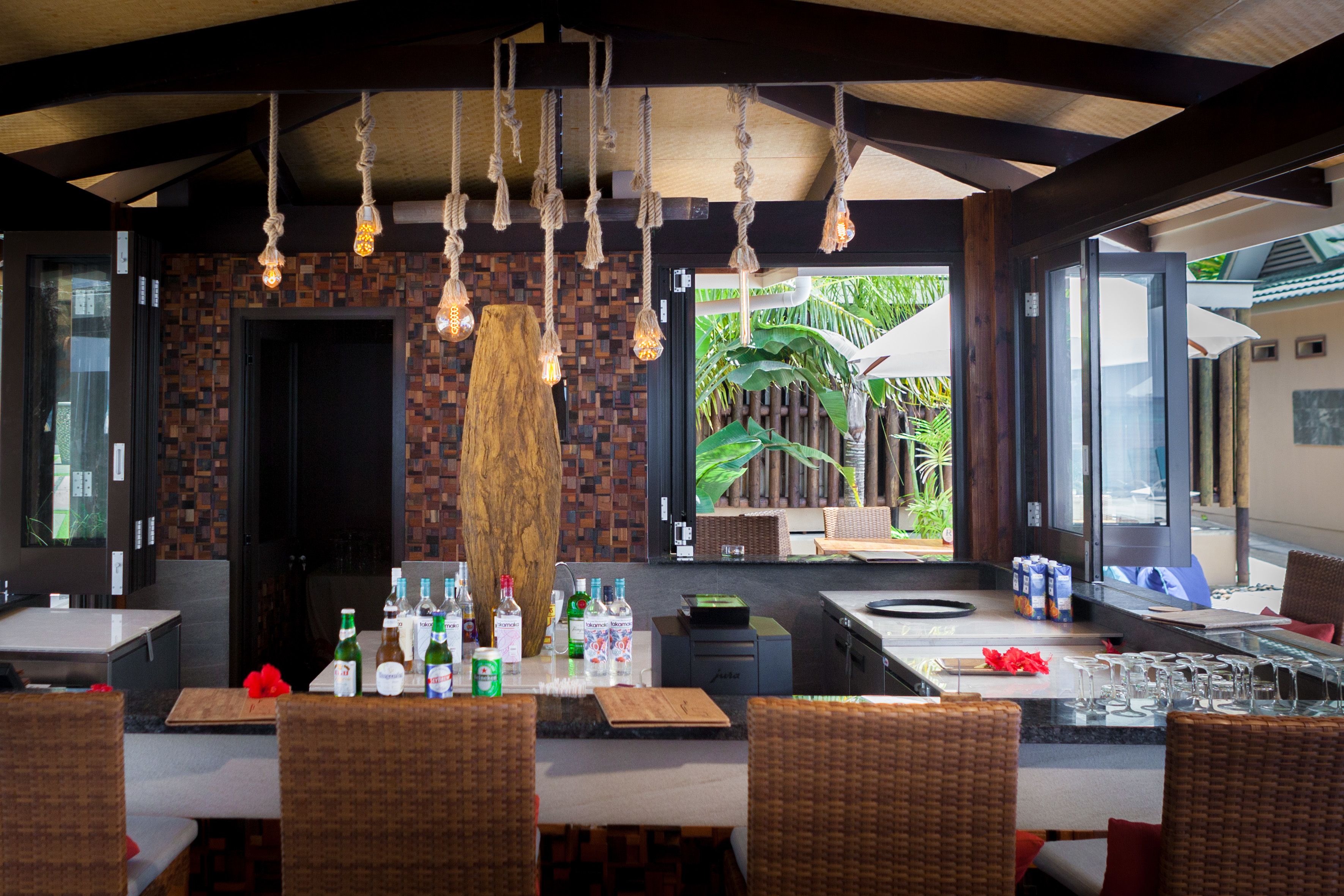 A restaurant with a brick wall, hanging light fixtures, and a view of the outdoors.