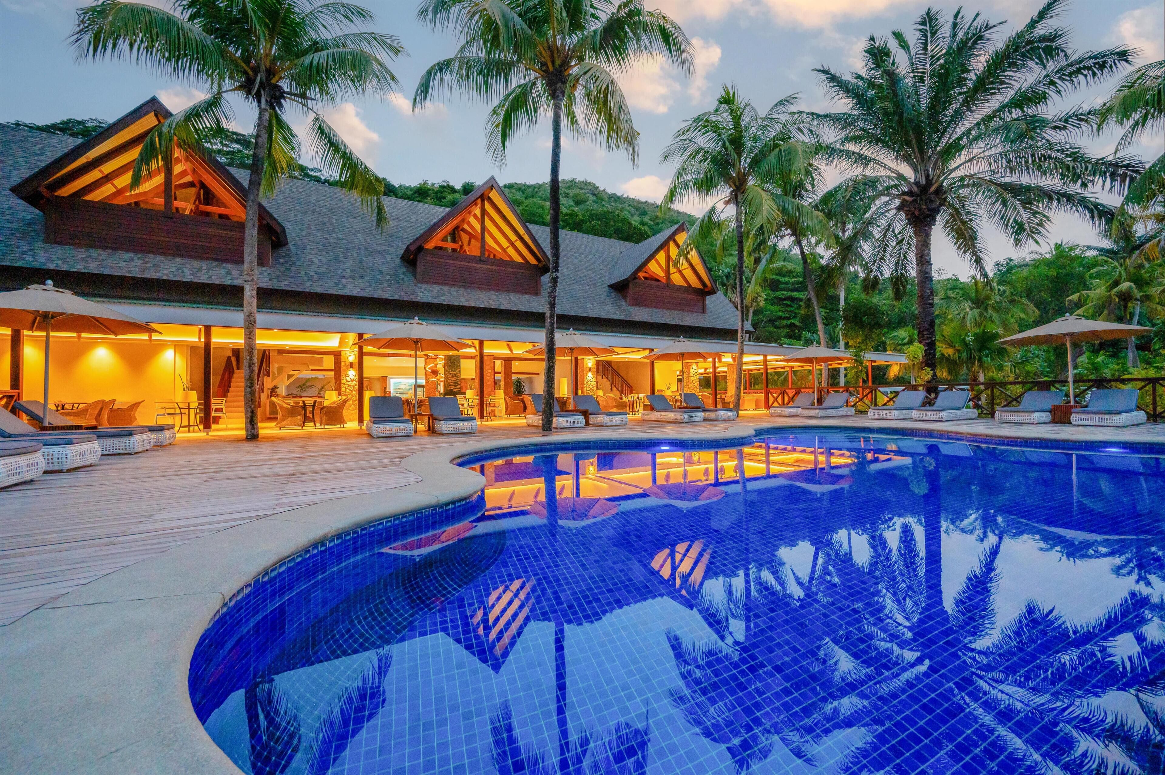Un resort con piscina, sillas de descanso y palmeras.