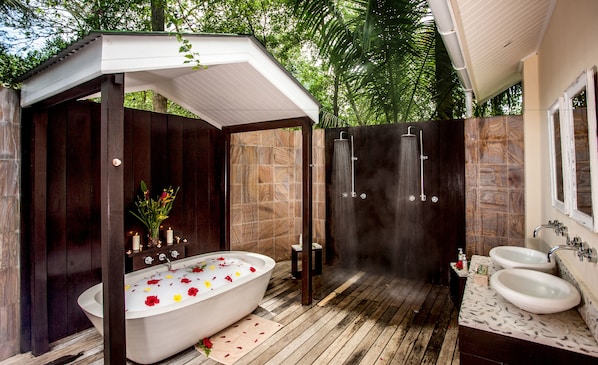 A modern outdoor bathroom with a freestanding bathtub, a shower enclosure, and two sinks. - Paradise Sun (Praslin Island)