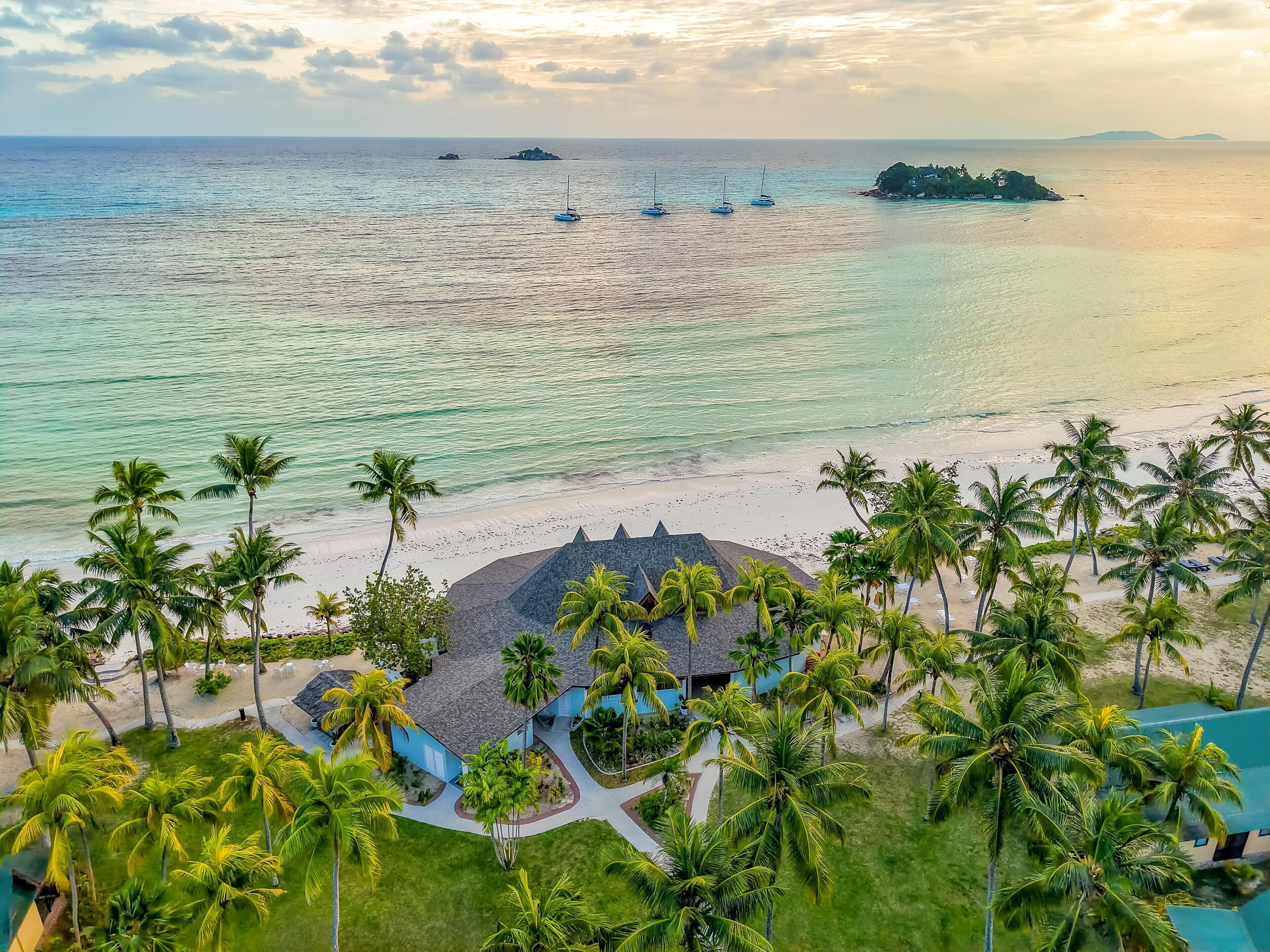 Un resort con playa, palmeras y vistas al océano.