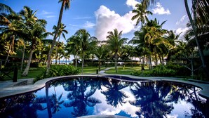 A swimming pool surrounded by palm trees and a clear sky. - Paradise Sun (Praslin Island)