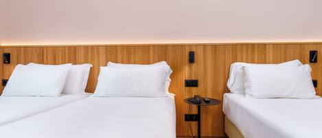 Una habitación de hotel con dos camas, una mesita redonda pequeña y un panel de pared de madera.