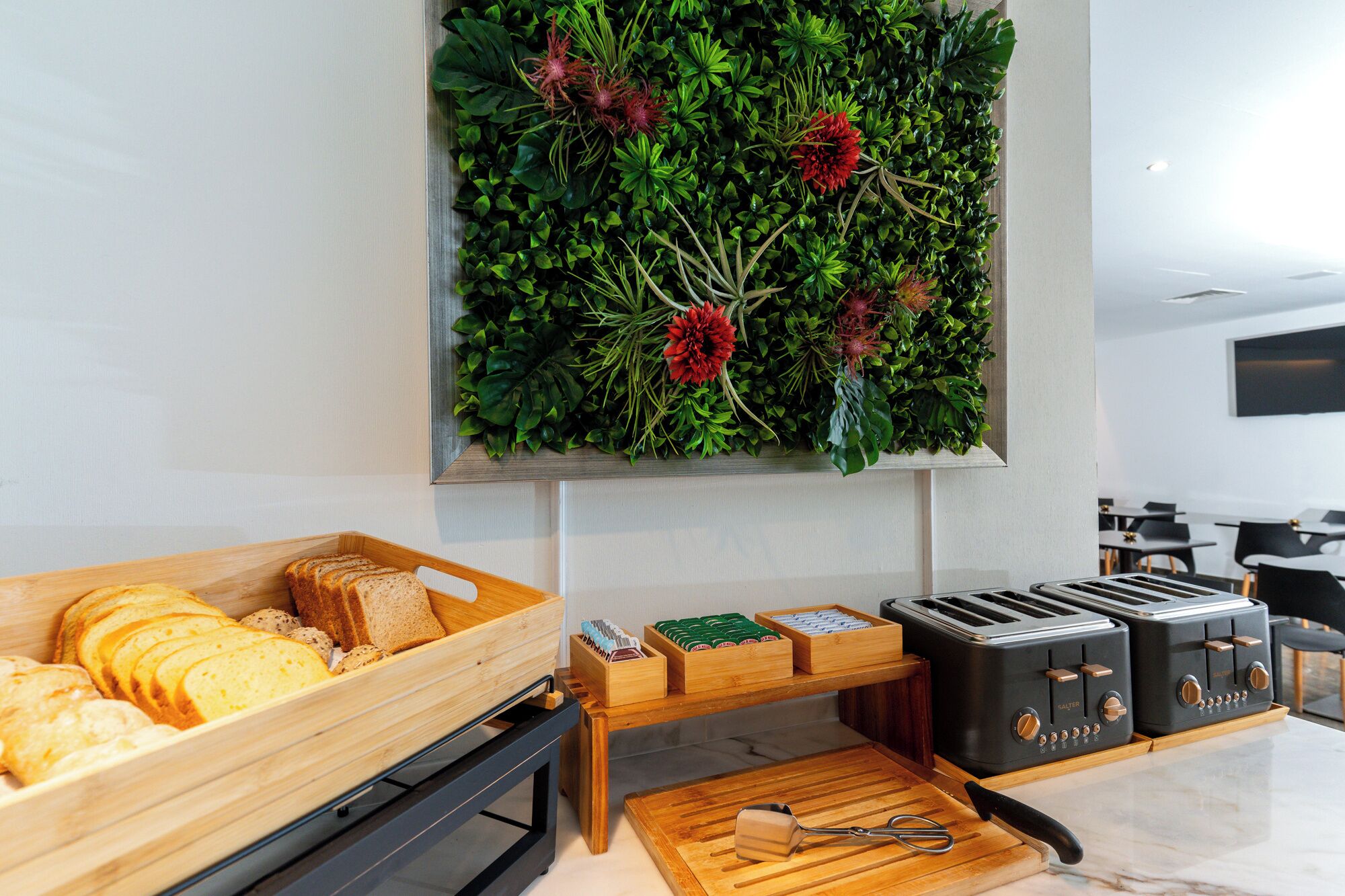 Una cocina con un expositor de pan, un tostador y una planta en la pared.
