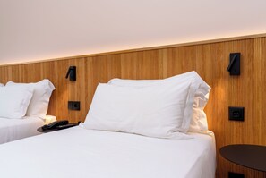 A hotel room with two beds, a bedside table, a lamp, and a wall-mounted control panel. - Cascais Hotel (Cascais)
