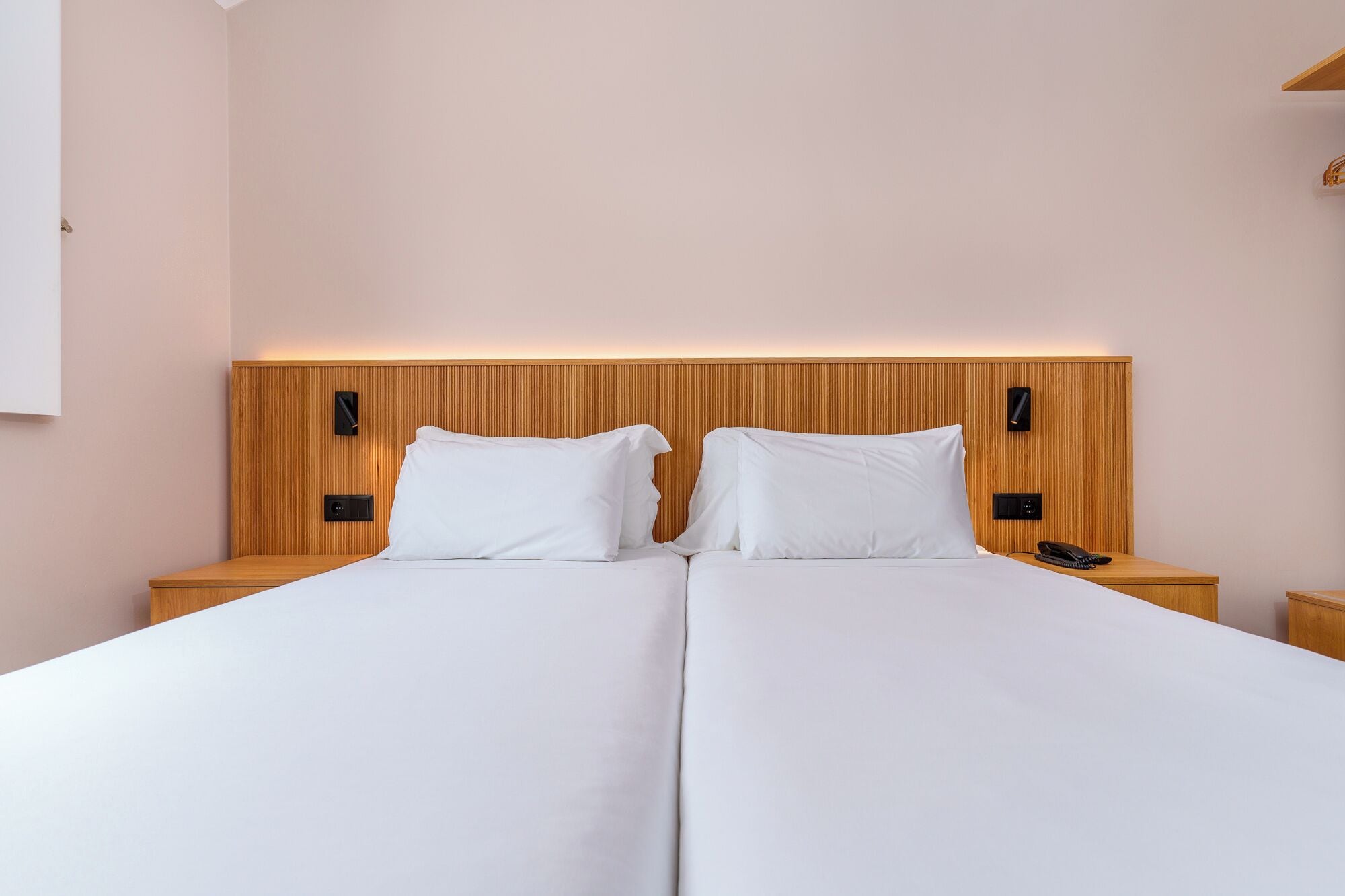 A double bed with a wooden headboard, two bedside tables with lamps, and a phone on one of the tables.