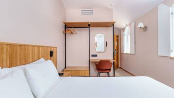 Une chambre d’hôtel comprenant un lit, un bureau, une chaise, un miroir et une armoire.