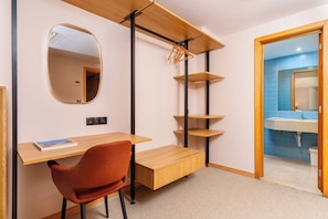 A room with a desk, chair, shelves, a mirror, and a bathroom with a sink. - Cascais Hotel (Cascais)
