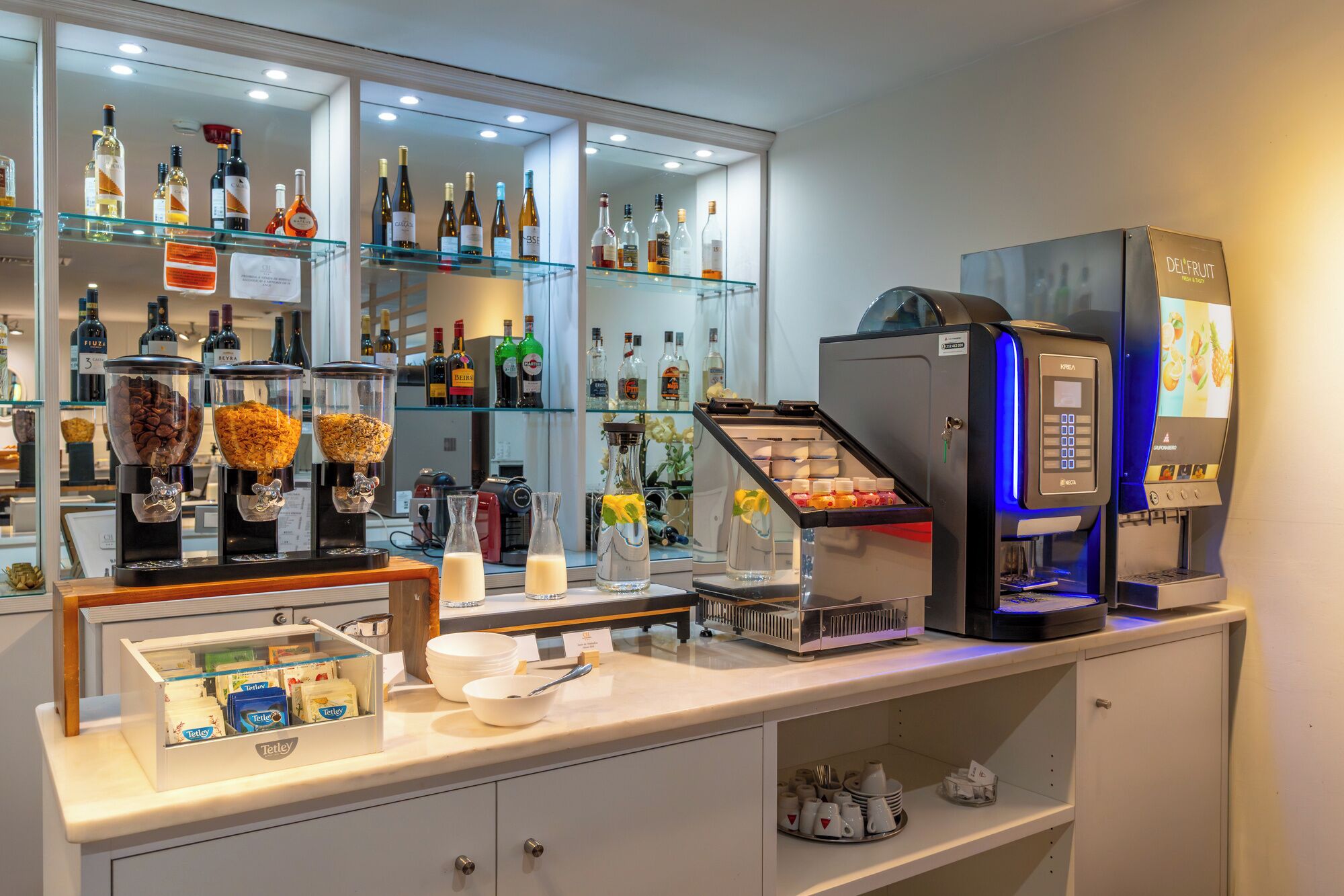 Una zona de bar con una máquina de café, diversas botellas de licor y un dispensador de café.