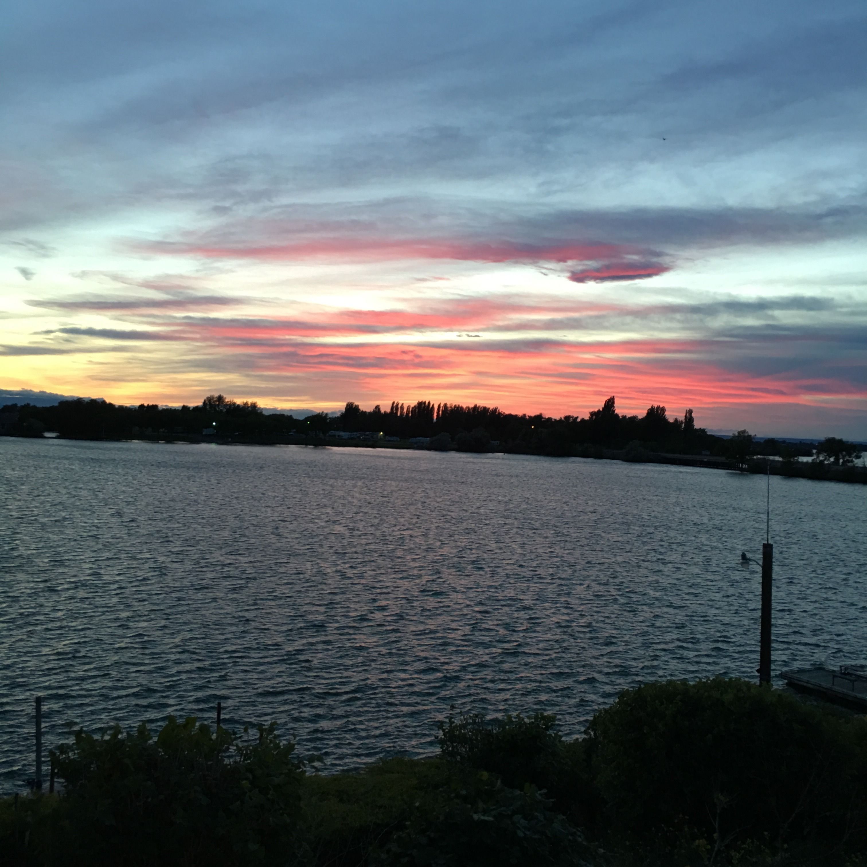 Un sol ponent sobre una massa d'aigua amb una riba llunyana.