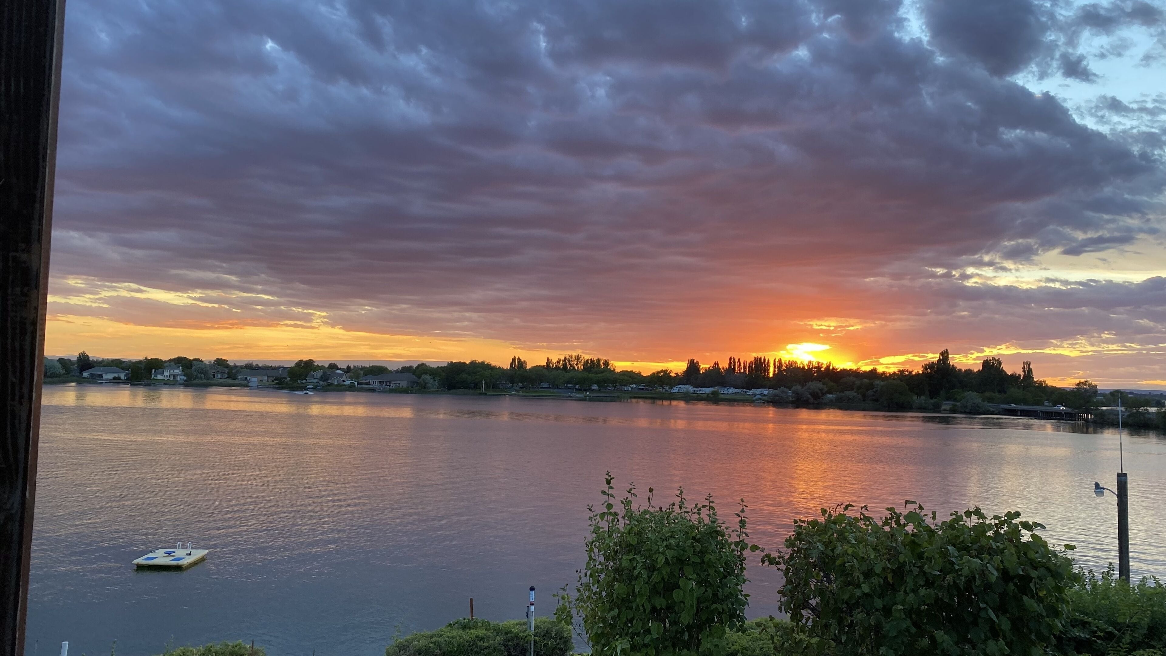A sunset over a calm body of water with a boat and a dock.