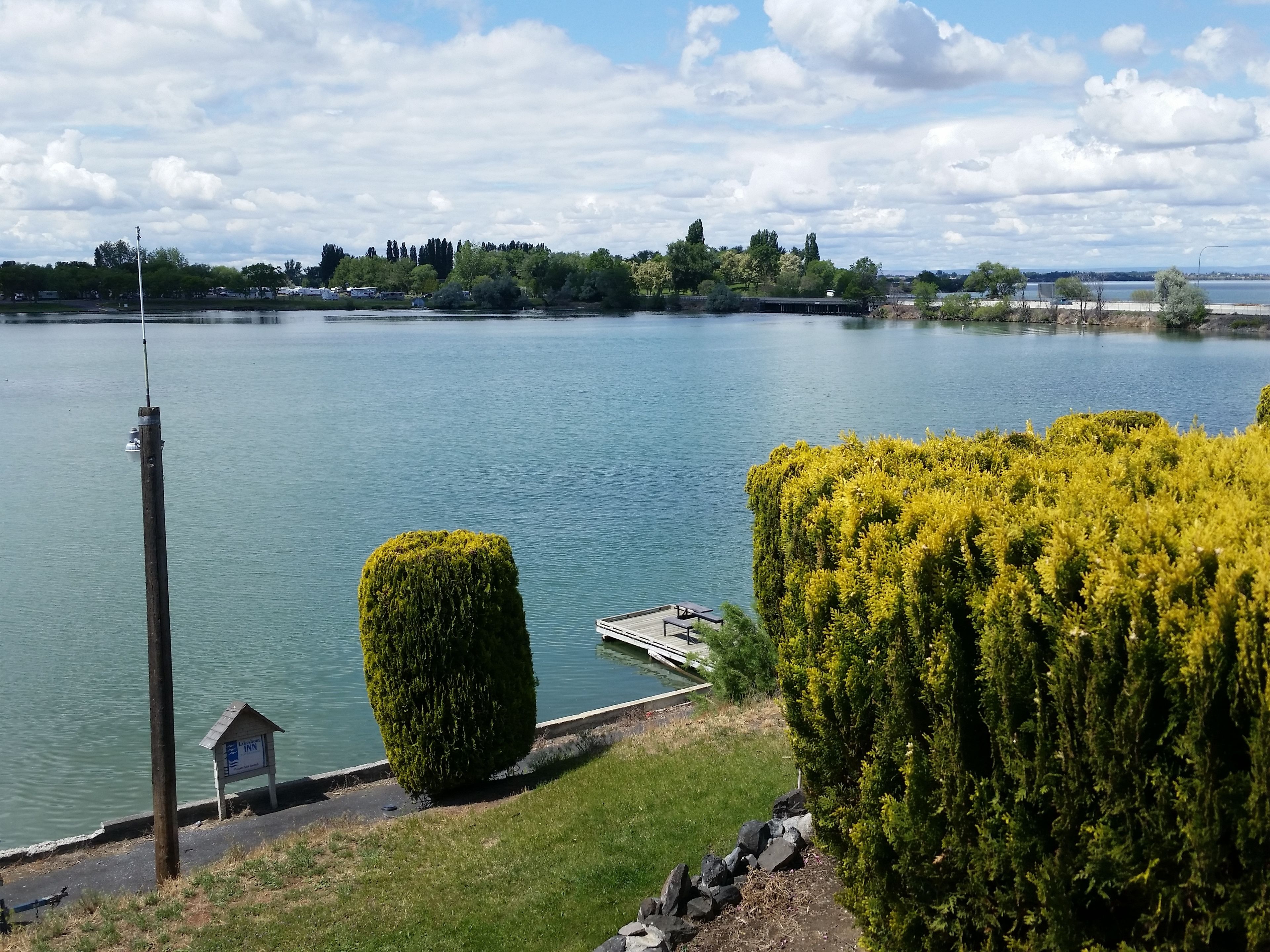 A lakeside view with a dock, a sign for 'Inn', and a well-maintained grassy area.