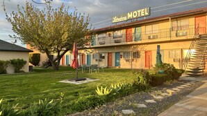 A motel with a sign, outdoor seating, and a well-maintained lawn. - Lakeshore Inn Water Front (Moses Lake)
