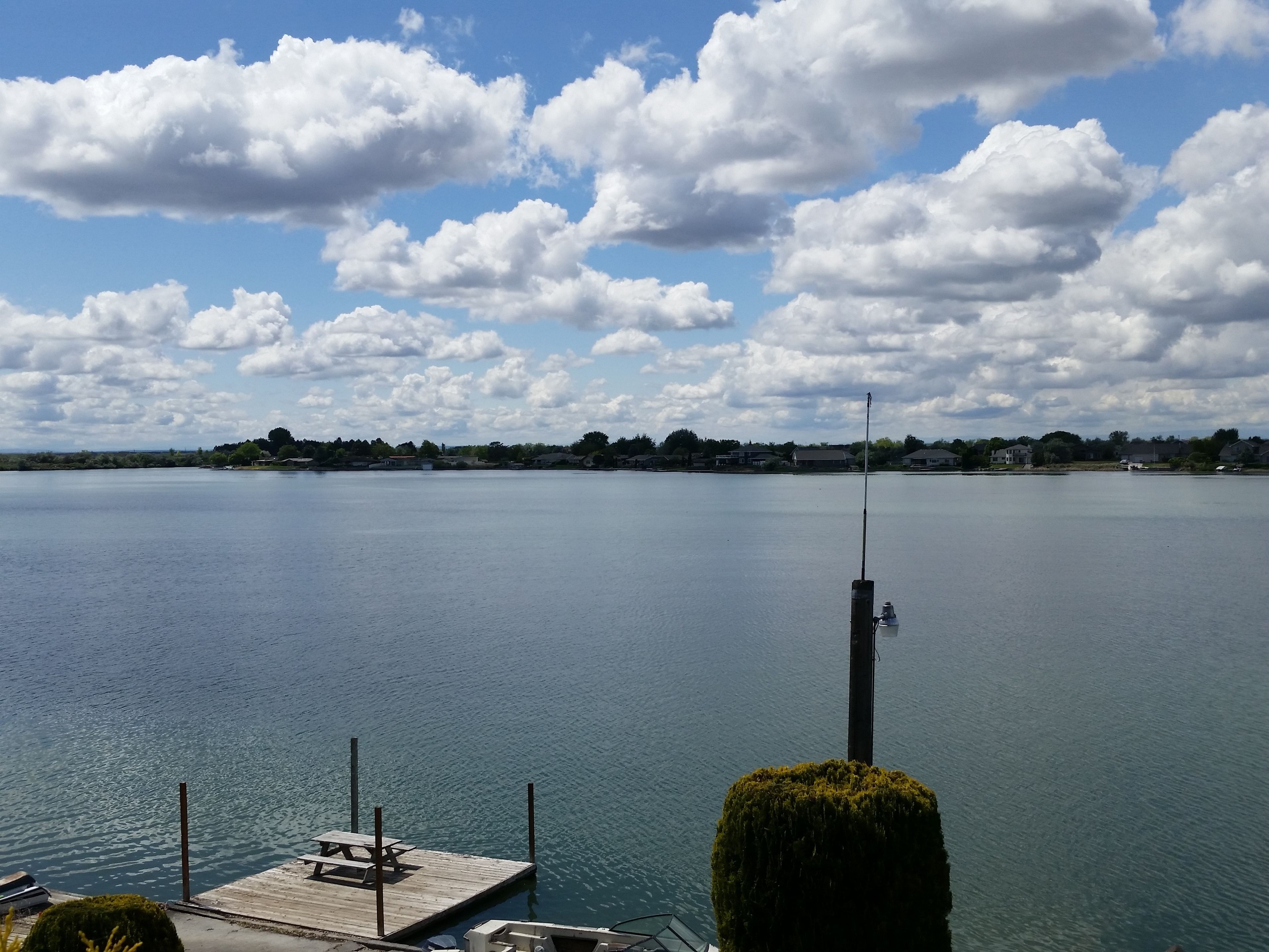 A calm lake with a dock and a picnic table.