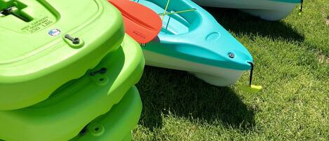 Una hilera de kayaks coloridos alineados en un césped cerca del agua.