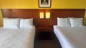 A hotel room with two single beds, a wooden headboard, a nightstand with two lamps, and a framed picture on the wall. - Lakeshore Inn Water Front (Moses Lake)