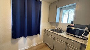 A small kitchen with a sink, a microwave, and a window above the sink. - Lakeshore Inn Water Front (Moses Lake)