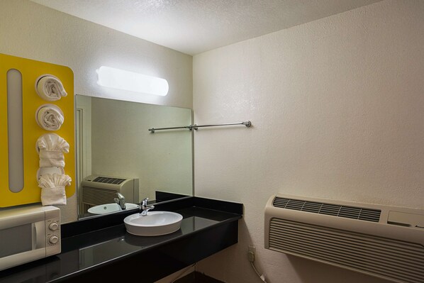 A bathroom with a black sink, a mirror, a towel rack, and a heater.
