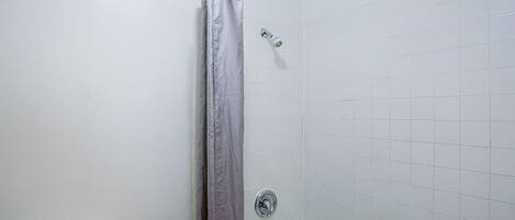 A bathroom with a shower, toilet, and bathtub.
