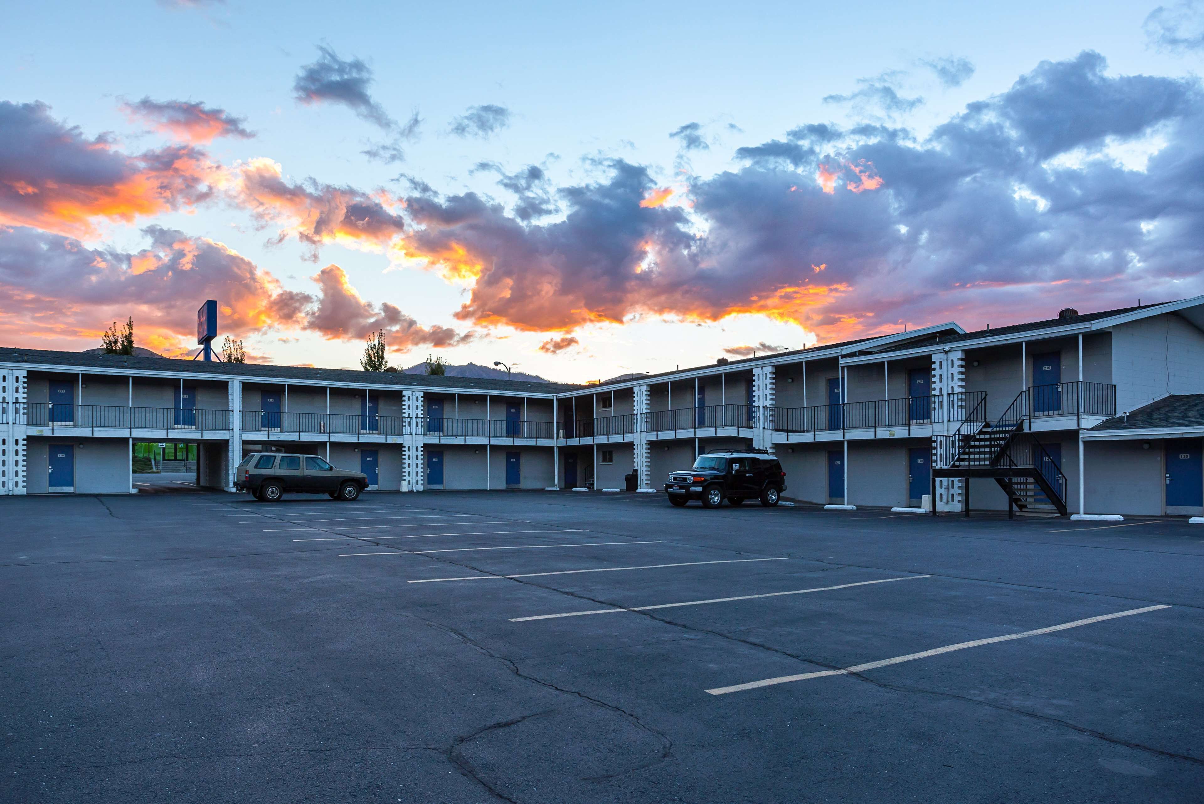 A motel with a parking lot, multiple floors, and a staircase leading to the upper levels.