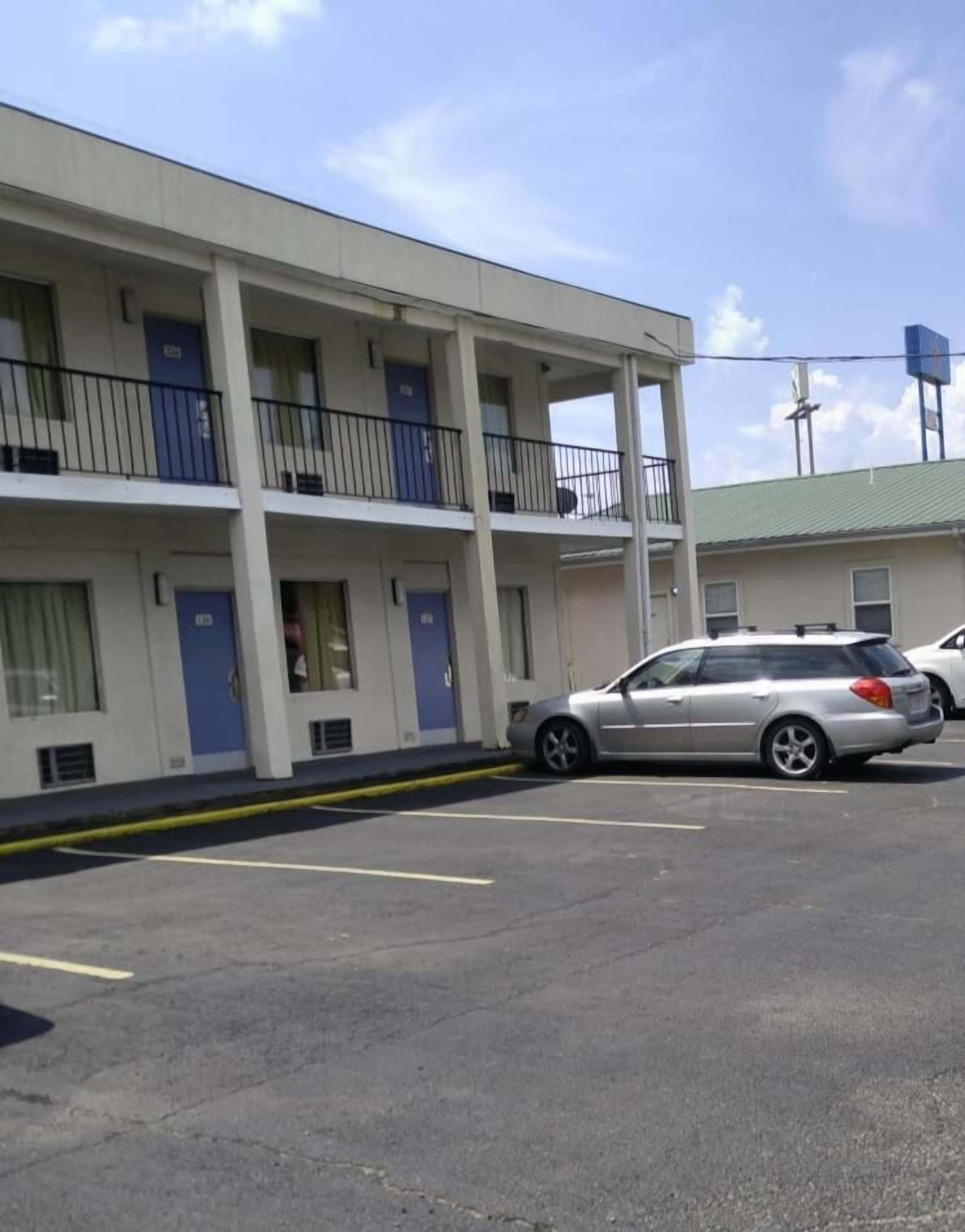 Un motel avec un bâtiment à deux étages, de nombreux balcons et un parking rempli de voitures.