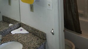 A bathroom with a sink, mirror, towel dispenser, and shower curtain. - Stay 4 Less (Fredericksburg)