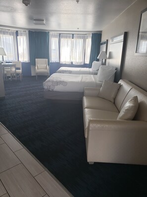 A hotel room with a large bed, a sofa, a desk, and a chair. - Anchor Beach Inn (Crescent City)