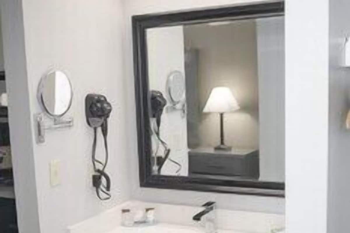 A bathroom with a white sink, a mirror, a hairdryer, and a lamp.