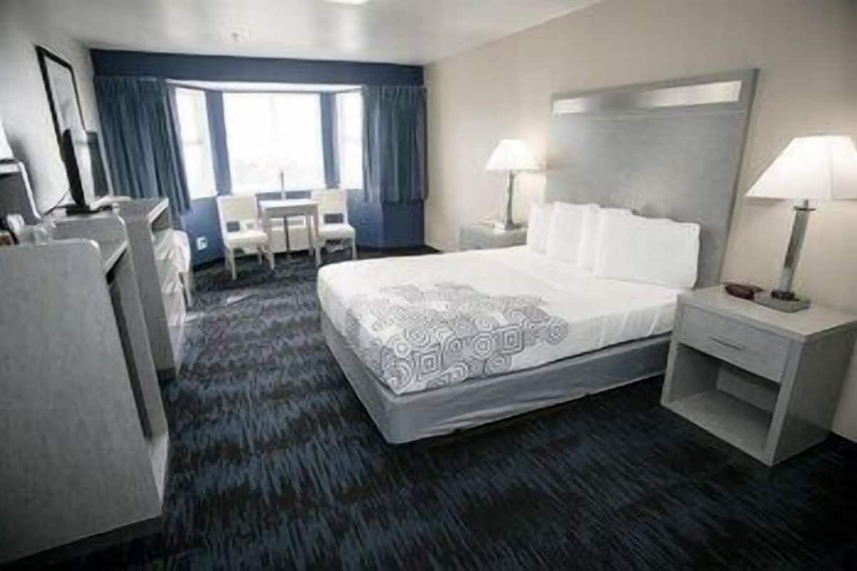 A hotel room with a bed, bedside tables, a desk, and a chair.