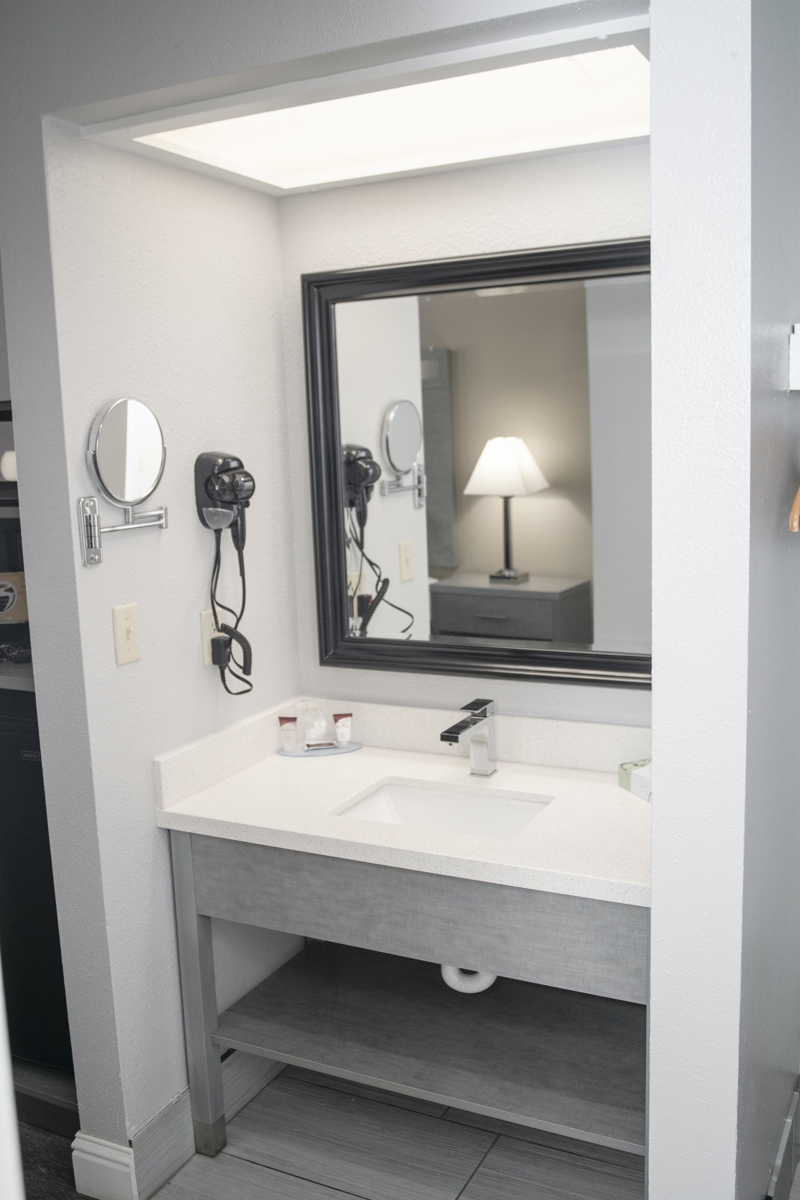Un baño de hotel con un lavamanos blanco, un espejo grande y un secador de pelo en la pared.