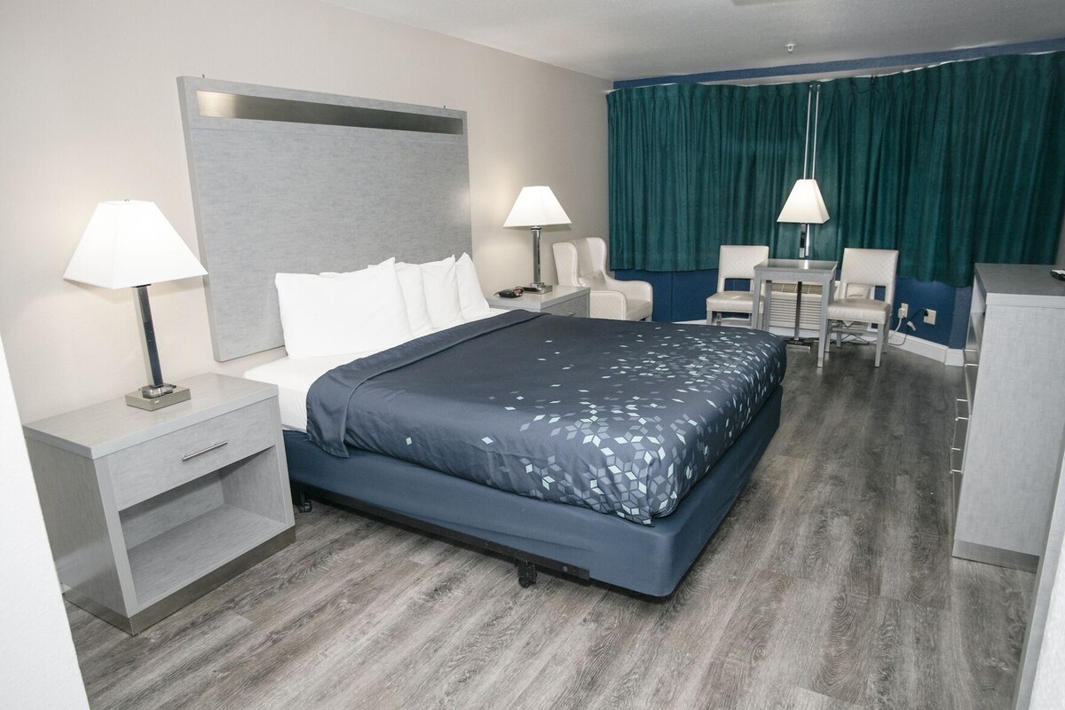 Ein modernes Hotelzimmer mit einem Bett, Nachttischen, einem Schreibtisch und einem Sessel.