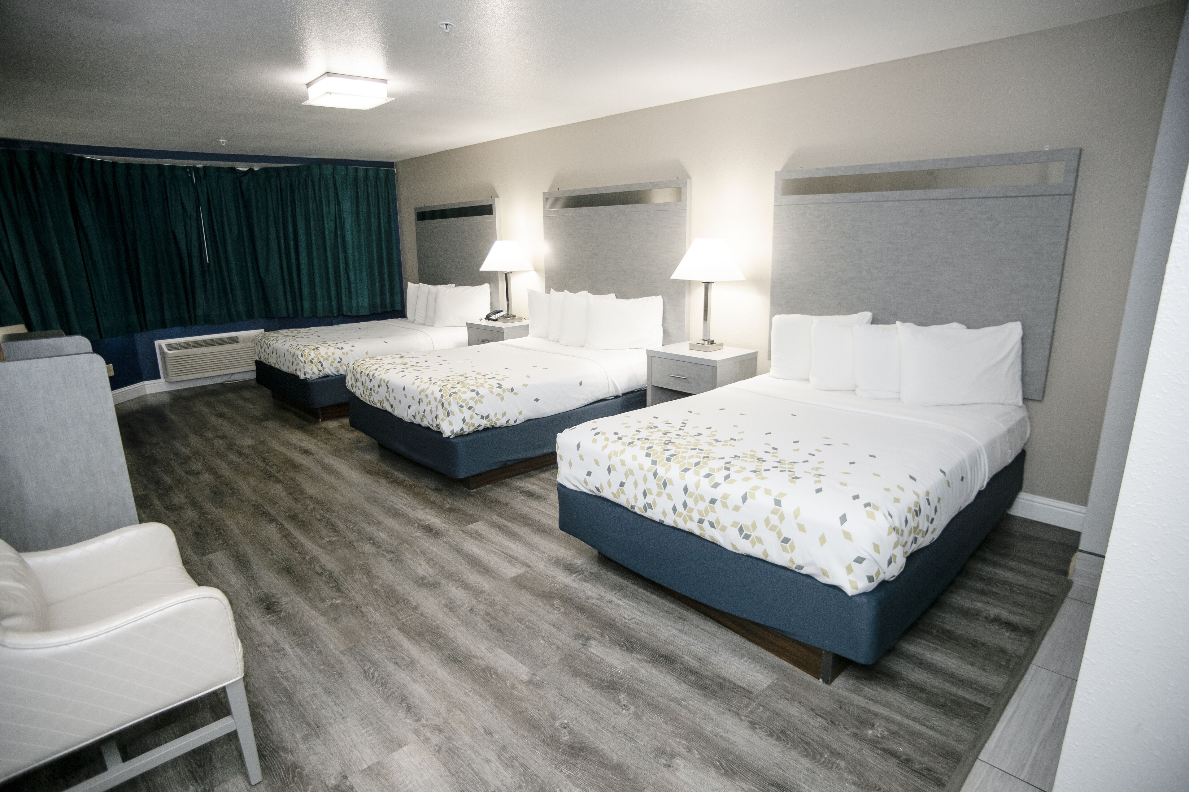A hotel room with two beds, a desk, and a chair.