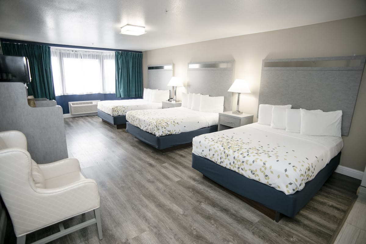A hotel room with two beds, a seating area, and a television.